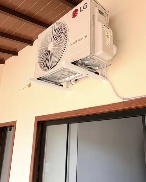 Condensadora LG instalada sob o forro de madeira da varanda, acima da porta